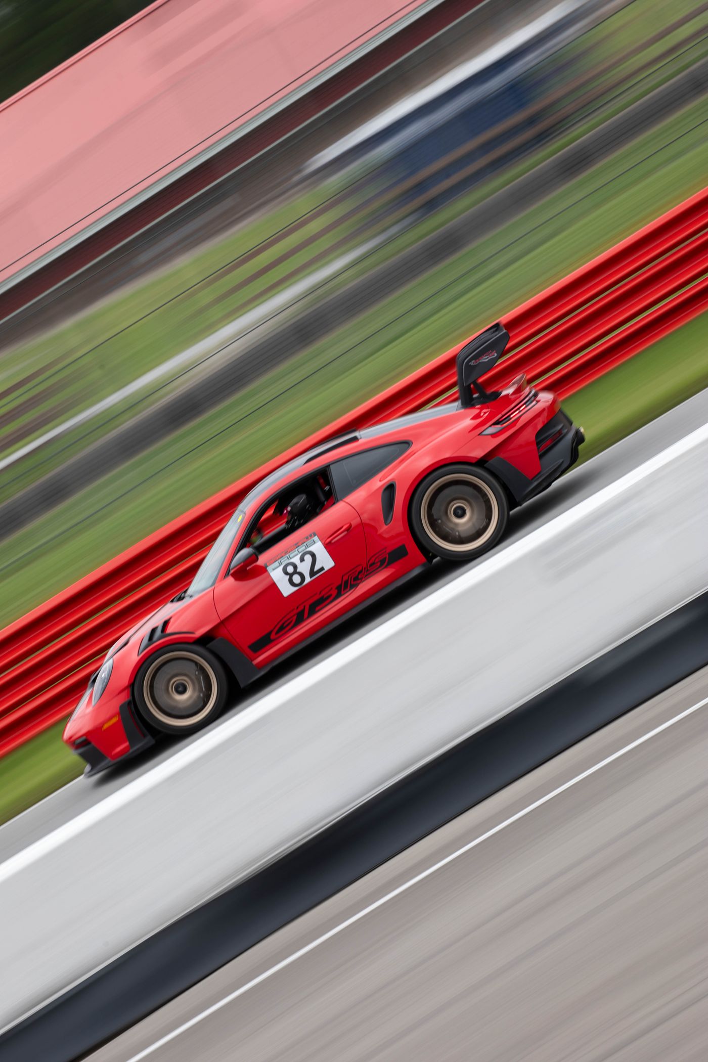 Bradshaw Autosport 992 GT3 RS #82 at speed past the red barriers at Mid-Ohio